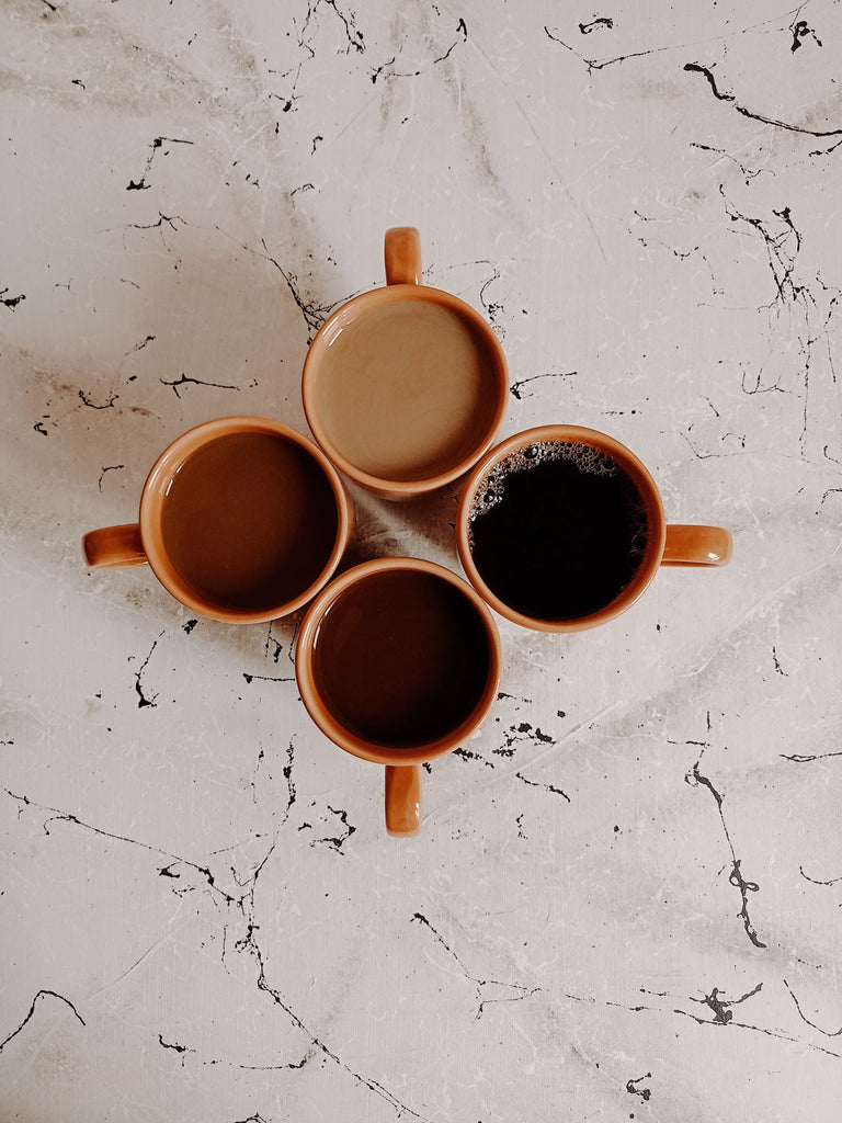 Four cups filled with coffee or tea prepared in different ways